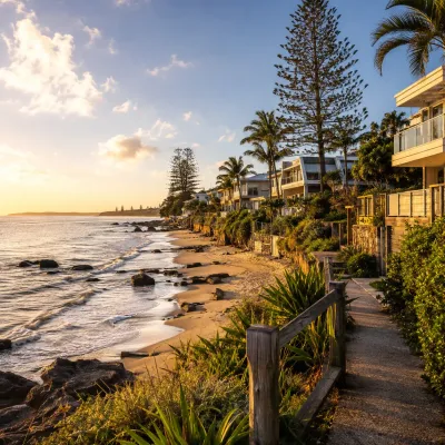 Queensland beachside homes beside a coastal walking path and sandy shoreline at golden hour, representing lifestyle-focused property investment in the state’s best seaside towns.