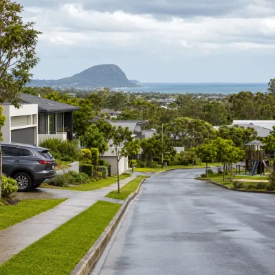 Family-friendly Peregian Springs streetscape with modern homes, park access and Mount Coolum in the distance, representing lifestyle and property buying across Peregian Springs and Coolum.