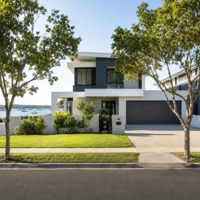 Modern bayside home in Wynnum and Manly with a landscaped lawn, street trees, and water views in the background.