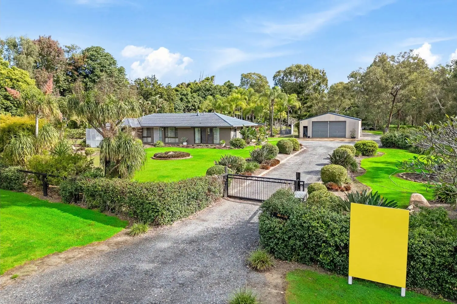 Elevated view of the acreage home, gated gravel driveway and large shed at 29–33 Birdsville Street, Greenbank