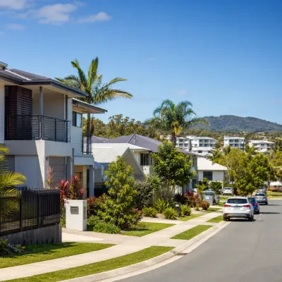 Affordable modern homes in a sunny Gold Coast suburb with palm trees and green hills, representing property entry points under $800k.