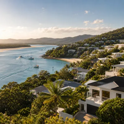Coastal homes overlooking a calm Noosa waterway with sandy beaches, boats and lush tropical surroundings, representing the Noosa property investment market in 2026.